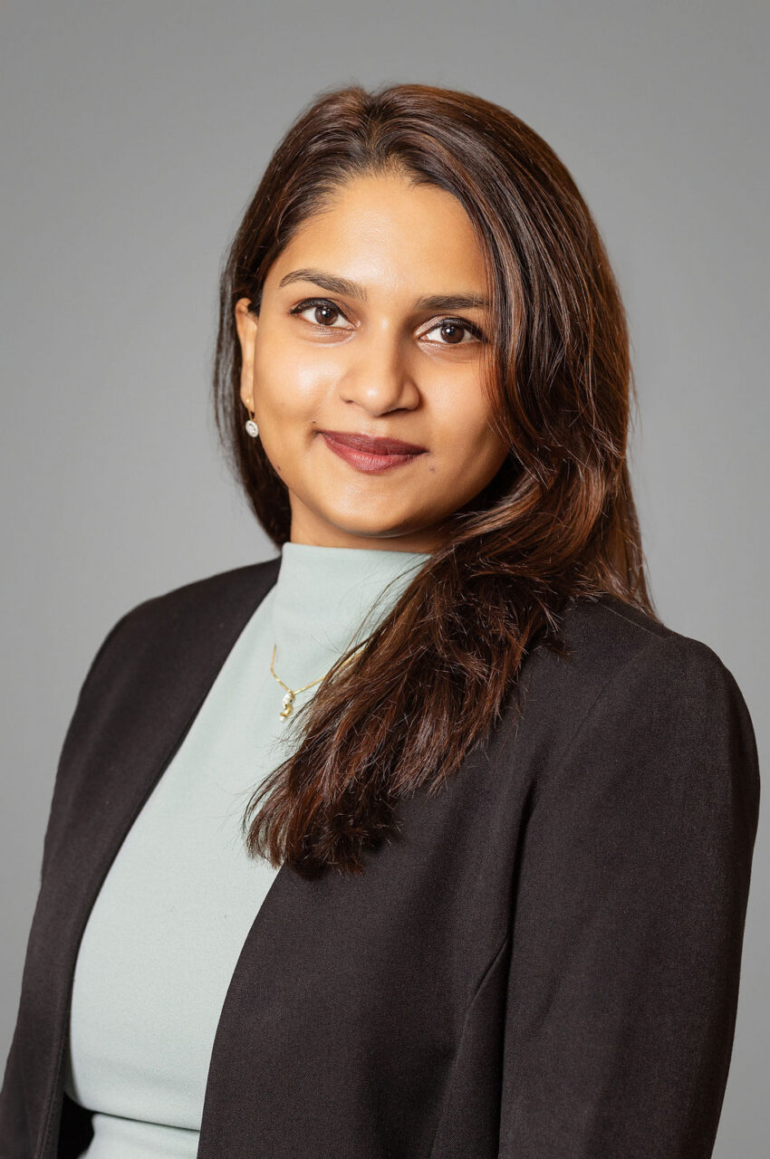 Professional headshot of Bhargavi Kannan wearing a black blazer over a light-colored top against a neutral gray background.
